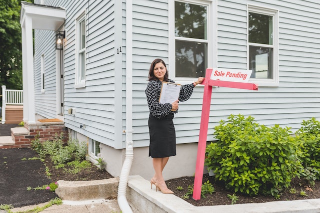 Real estate agent next to a sale pending sign.